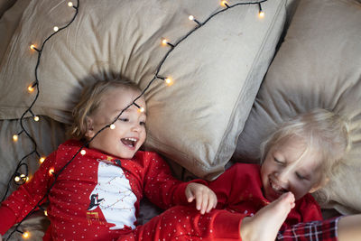 High angle view of cute sisters lying on bed