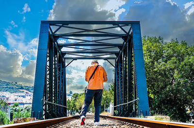 Rear view of woman standing on bridge against sky