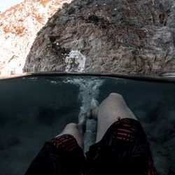 Low section of person on rock by sea