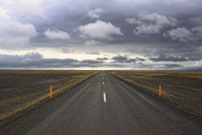 Empty country road against cloudy sky