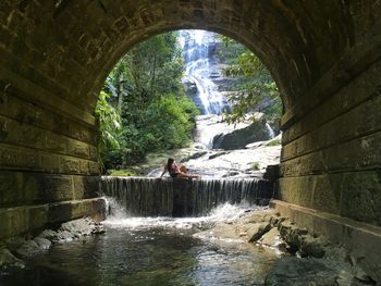 Woman sitting by waterfall