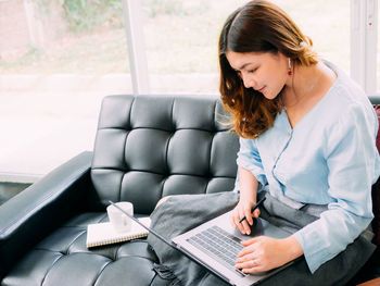 Woman using mobile phone while sitting on sofa