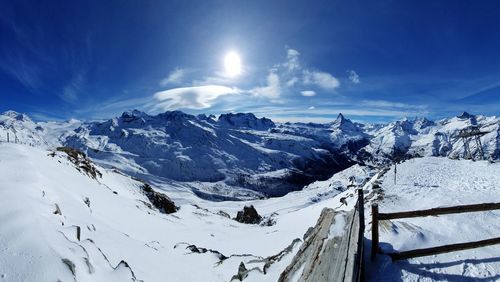 Scenic view of snow covered mountains against blue sky