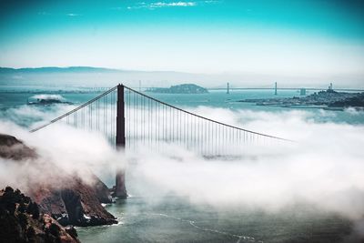 Golden gate bridge over sea against sky during foggy weather