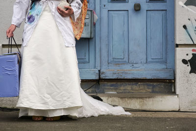 Low section of woman standing against white wall