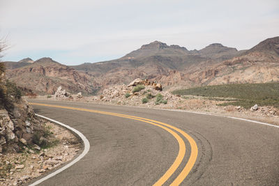 Empty road by mountains against sky