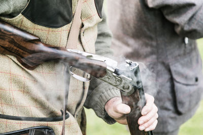 Midsection of man holding rifle outdoors