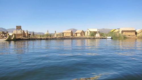 View of buildings by river against clear blue sky