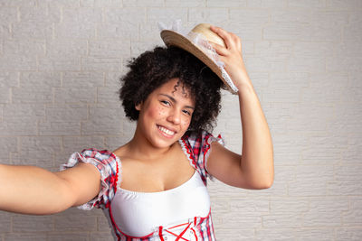 Portrait of a smiling young woman against wall