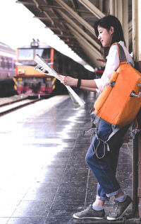 Woman reading map while standing at railroad station platform