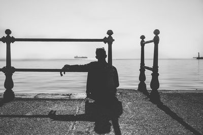 Silhouette people standing by sea against clear sky