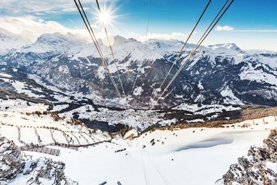 Scenic view of snow covered mountains against bright sun