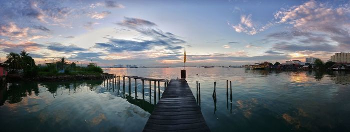 Pier over lake against sky during sunset