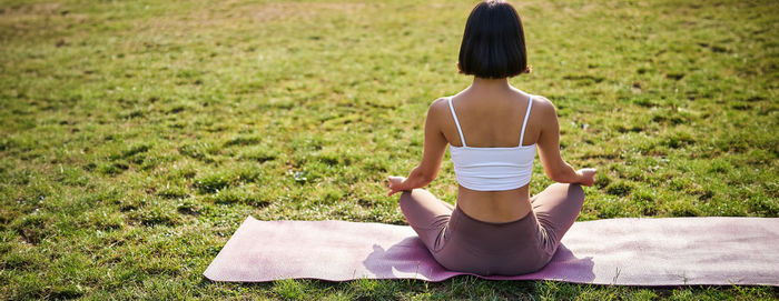 Rear view of woman sitting on grassy field