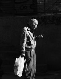 Full length of man looking at camera while standing on wall