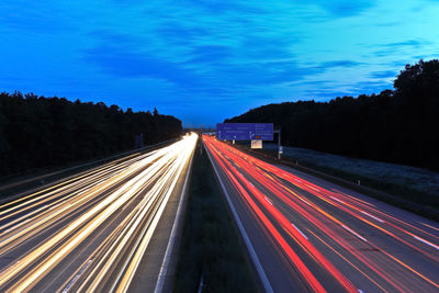 Light trails on road against sky at night