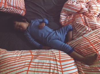 High angle view of girl sleeping on bed