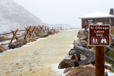 Sign board by rocks during winter