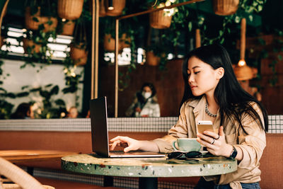 Young woman using smart phone in restaurant