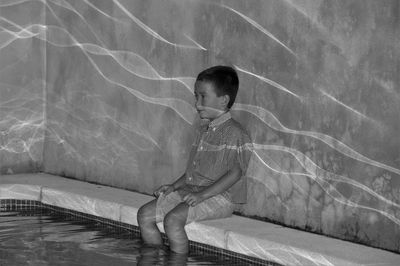 Cute boy sitting in swimming pool