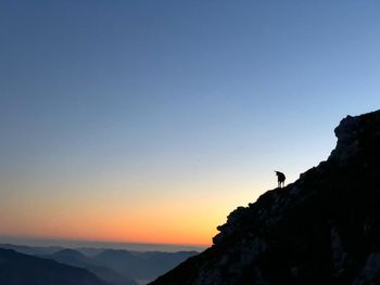 Scenic view of silhouette mountains against clear sky during sunset