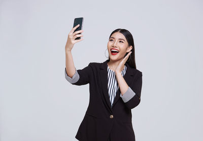 Young woman using smart phone against white background