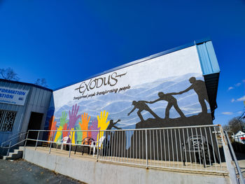 Low angle view of graffiti on wall against clear blue sky