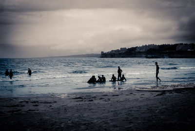Silhouette people on beach against sky