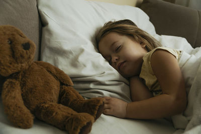 Portrait of cute little girl sleeping in bed with toy bear