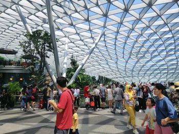 People at amusement park in city against sky