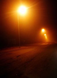 Illuminated street light on road at night