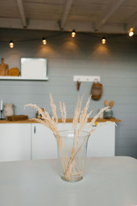 Dry grass branches in a glass vase on the table in the scandinavian kitchen