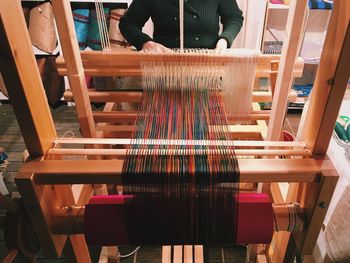 Female worker weaving while using loom in workshop
