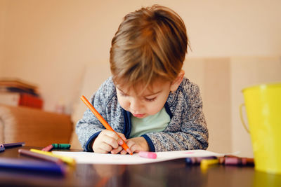 Boy looking at camera while sitting on table