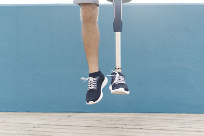 Disabled man jumping against blue wall