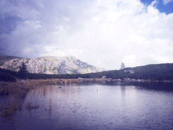 Scenic view of lake and mountains against cloudy sky