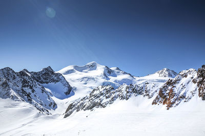 Snow covered mountains against clear blue sky