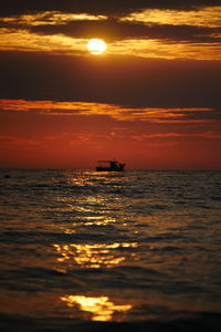 Scenic view of sea against dramatic sky during sunset