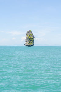 Scenic view of rock in sea against sky