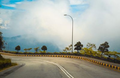 Road by trees against sky