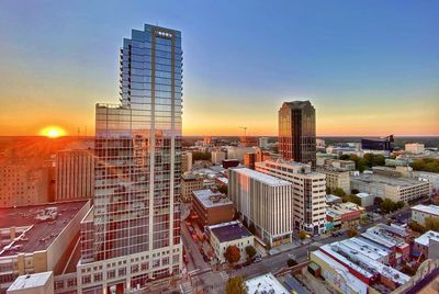Modern buildings in city against sky during sunset