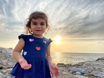 Girl on beach against sky during sunset