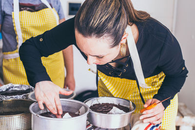 Young chef examining chocolate in container at table