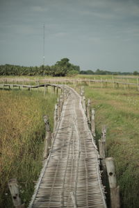 Boardwalk on field against sky