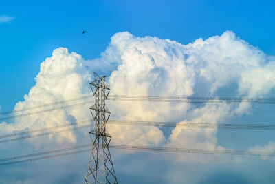 Low angle view of electricity pylon against cloudy sky