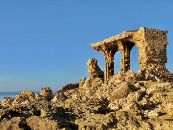 Low angle view of rock formation against clear blue sky