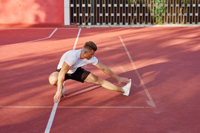 Full length of young woman exercising on court