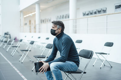 Businessman wearing protective face mask with tablet pc in corridor