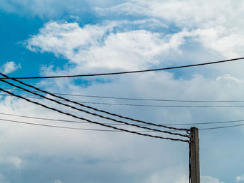 Low angle view of power cables against sky