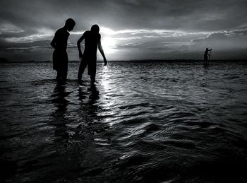 Silhouette people on calm beach